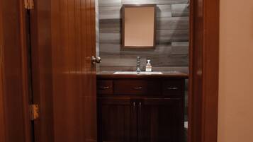 A bathroom with a wooden vanity, a mirror, and a sink.