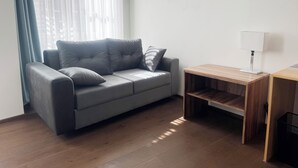 Una sala de estar moderna con un sofá gris, una mesita de madera y una lámpara.