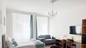 Una habitación de hotel moderna con una cama, un sofá, un escritorio, un televisor y una araña.