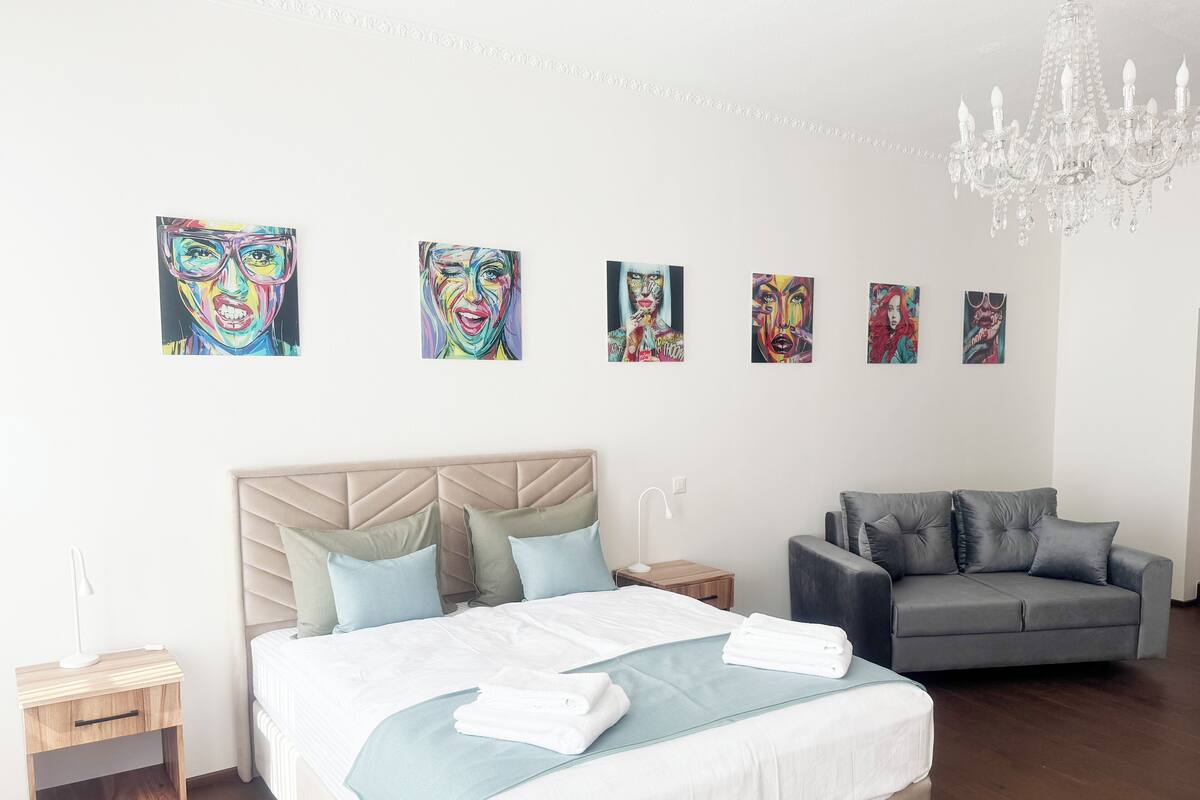 Een moderne hotelkamer met een groot bed, een grijze bank en kunst aan de muur.