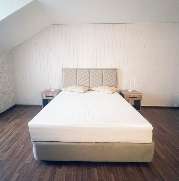 Un lit simple dans une chambre au plancher en bois et au plafond en pente.
