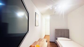 A modern hotel room with a large window, a wooden table with breakfast items, a bed, and a headboard.