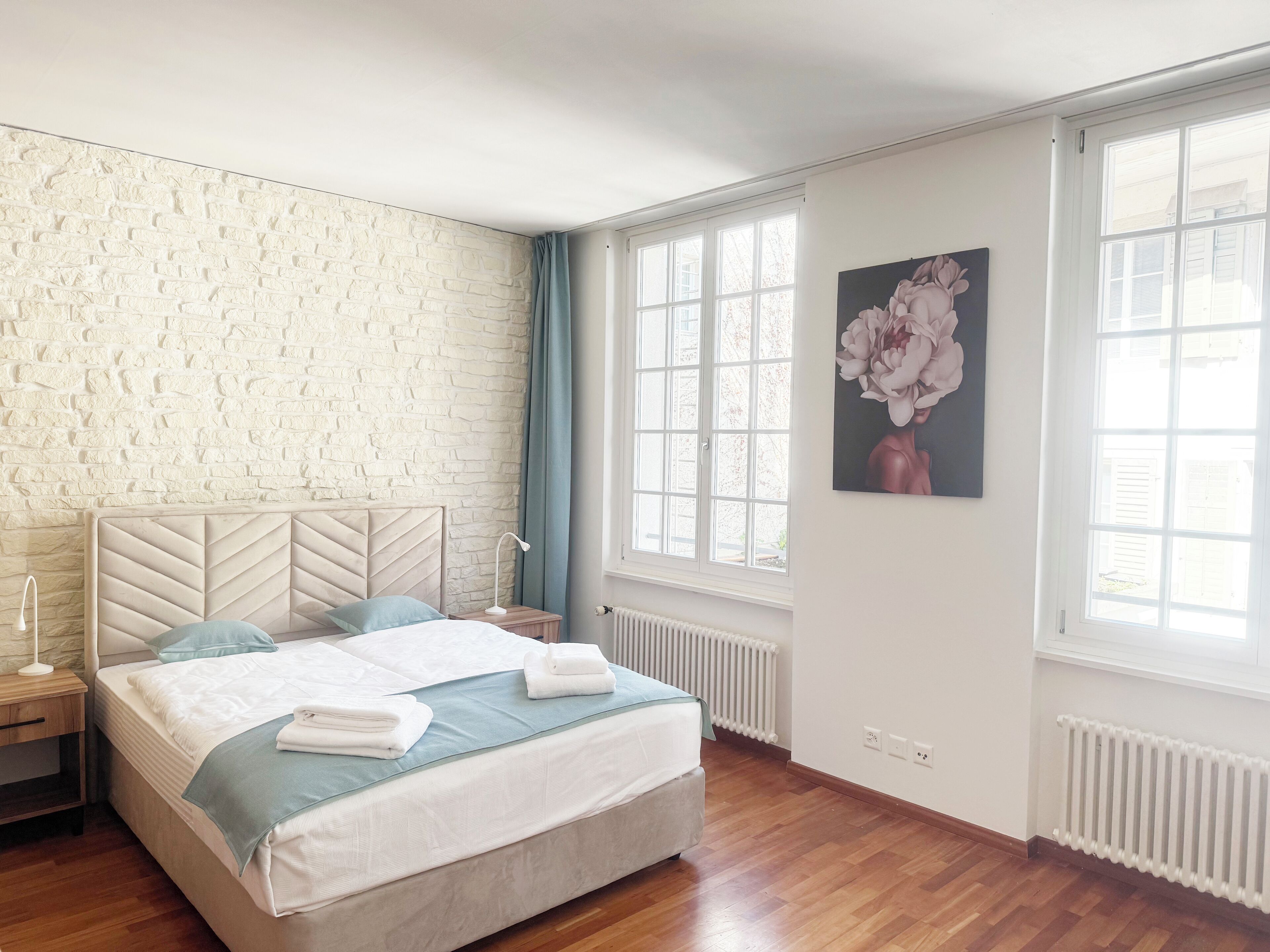 Ein Schlafzimmer mit einem großen Bett, einer Ziegelwand, einem Fenster und einem Gemälde.