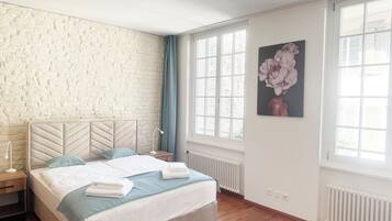 Ein Schlafzimmer mit einem großen Bett, einer Ziegelwand, einem Fenster und einem Gemälde.
