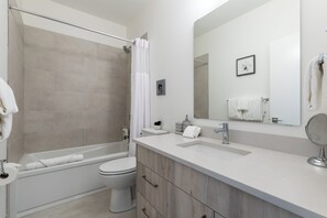 A modern bathroom with a bathtub, toilet, and sink. - OSO Summit - Downtown Riverfront Condo with Mountain Views (Golden)