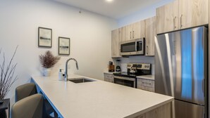 A modern kitchen with a central island, stainless steel appliances, and light wood cabinetry. - OSO Summit - Downtown Riverfront Condo with Mountain Views (Golden)
