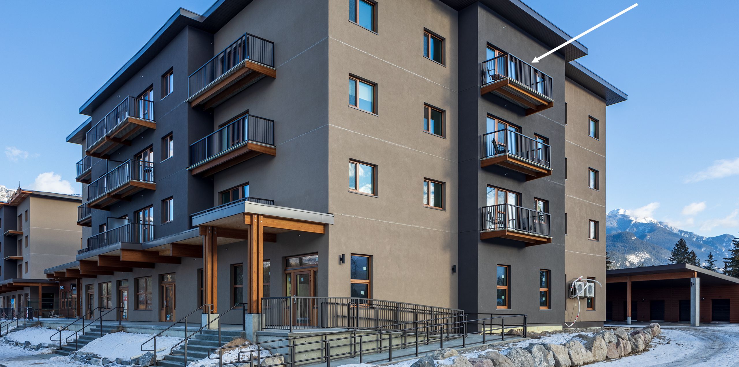 A multi-story building with balconies and a ski slope in the background.