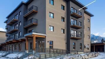A multi-story building with balconies and a ski slope in the background.