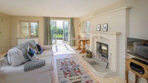 A living room with a fireplace, a sofa, a television, and a view of the outdoors.