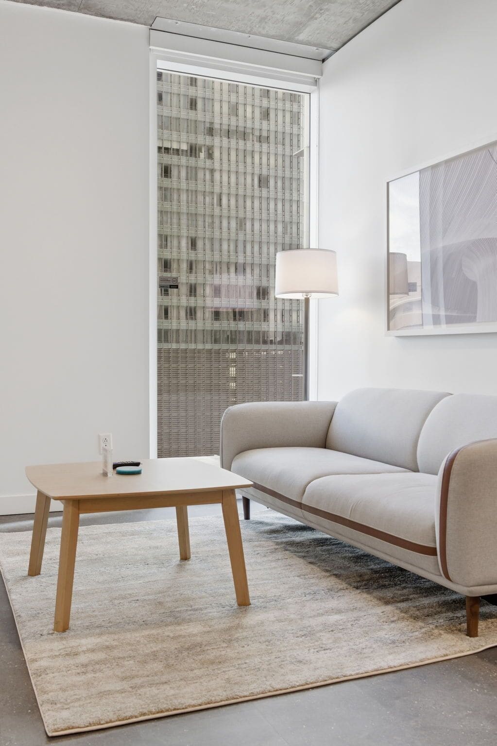 Un salon moderne avec un canapé, une petite table et une lampe.