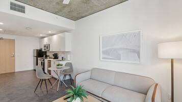 A modern living room with a sofa, a coffee table with a plant, and a dining area with chairs and a table.