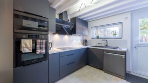 A modern kitchen with a built-in oven, a dishwasher, and a window above the sink.