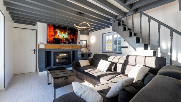 A modern living room with a fireplace, a sofa set, and a staircase.