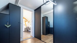 A modern room with dark wooden cabinets, a wooden floor, and a large mirror reflecting the room.