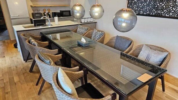 A modern kitchen with a central island, a dining area with wicker chairs, and pendant lighting. - Private Villa isola (Tokunoshima)