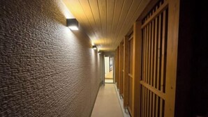 A narrow hallway with textured walls and wooden doors on the right. - Private Villa isola (Tokunoshima)