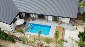 A modern house with a swimming pool, outdoor seating, and a covered patio area. - Private Villa isola (Tokunoshima)