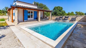 A poolside area with a pool, lounge chairs, and a building with blue shutters. - Beautiful home in Krnica (Krnica)