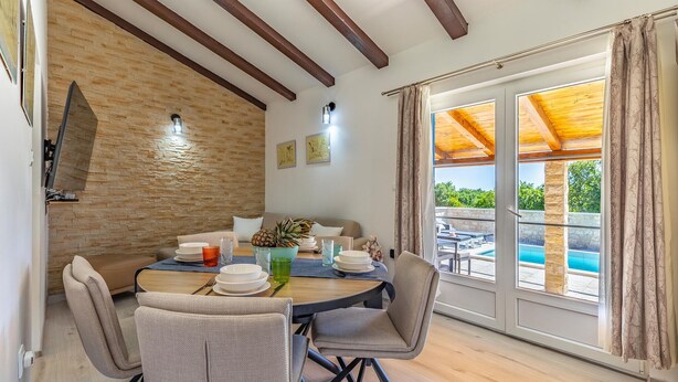 A dining area with a wooden table, chairs, and a view of a swimming pool. - Beautiful home in Krnica (Krnica)