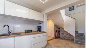 A modern kitchen with white cabinets, a black faucet, and a coffee maker on the counter. - Beautiful home in Krnica (Krnica)