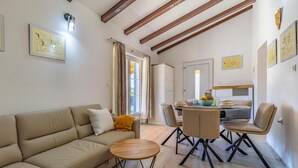 A spacious living room with a sofa, a small round table, and a dining area with chairs and a table set for two. - Beautiful home in Krnica (Krnica)