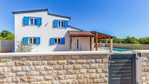 A two-story house with blue shutters, a stone wall, and a pool area. - Beautiful home in Krnica (Krnica)