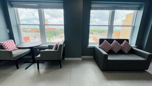 Una habitación moderna con dos sofás grises, una mesita redonda y ventanas amplias con vistas a la ciudad.