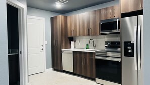Une cuisine moderne avec des meubles en bois, des appareils en acier inoxydable et une porte blanche.