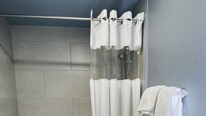 A bathroom with a bathtub, shower curtain, toilet, and towel rack. - Downtown Historic 1 Bed 1 Bath Apartment Unit 202 (Temple)