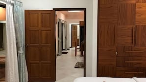 Una camera d'albergo con un letto, un armadio in legno e una porta che dà su un corridoio.