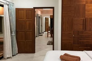 A hotel room with a bed, a wooden wardrobe, and a door leading to a hallway. - The Pool House Pattaya No.8 (Pattaya)