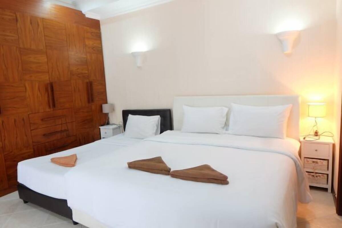 Une chambre à coucher avec un lit, des tables de chevet et une armoire en bois.