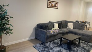 A living room with a sectional sofa, a coffee table, a shaggy rug, and a potted plant. - Cozy quiet place 15 min driver to airport perfect place for family and friends. (Calgary)