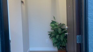 A hallway with a wooden door, a potted plant, and a light fixture on the ceiling. - Cozy quiet place 15 min driver to airport perfect place for family and friends. (Calgary)