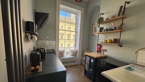 Una cocina compacta con ventana, electrodomésticos integrados y estantes de madera.