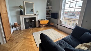 Una sala de estar con chimenea, un sofá, un televisor y una ventana con vista a la ciudad.