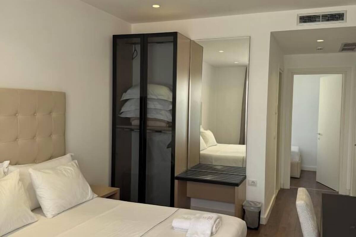 Une chambre d’hôtel avec un lit, une armoire, une petite table et un miroir.