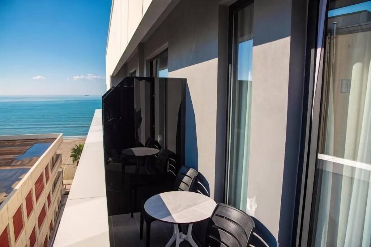 Un balcon avec une table et des chaises, donnant sur la mer.