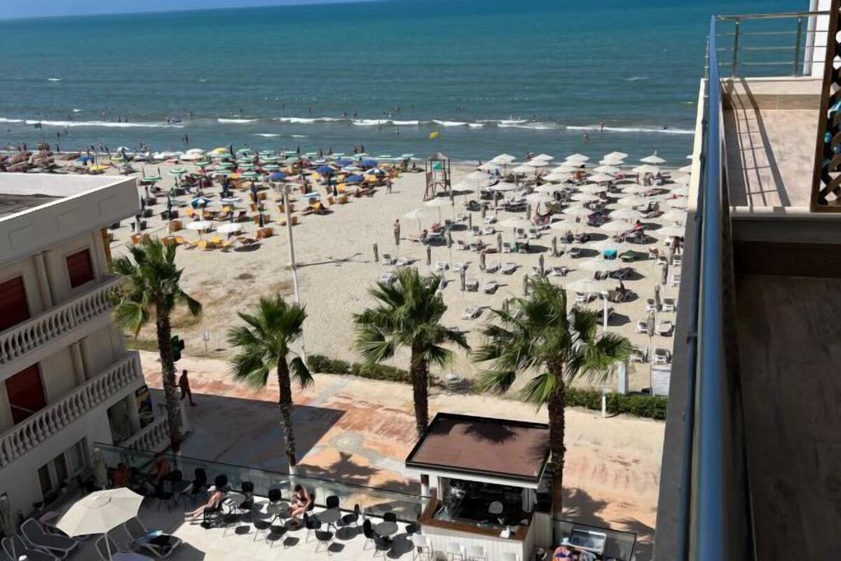 Un hôtel situé en bord de mer, doté d’une terrasse, de palmiers et offrant une vue sur l’océan.