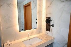 A bathroom with a marble sink, a mirror, and a wall-mounted phone. - Adria Palace (Durres)