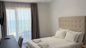 Habitación de hotel con cama, escritorio y ventana con cortinas.
