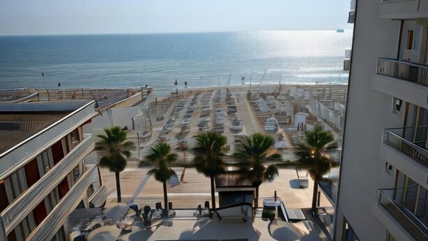 Un hotel frente a la playa con estacionamiento, palmeras y vista al océano.