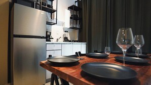 Una cocina moderna con un refrigerador de acero inoxidable, un horno empotrado y una cafetera. Hay copas de vino sobre la mesa de comedor.