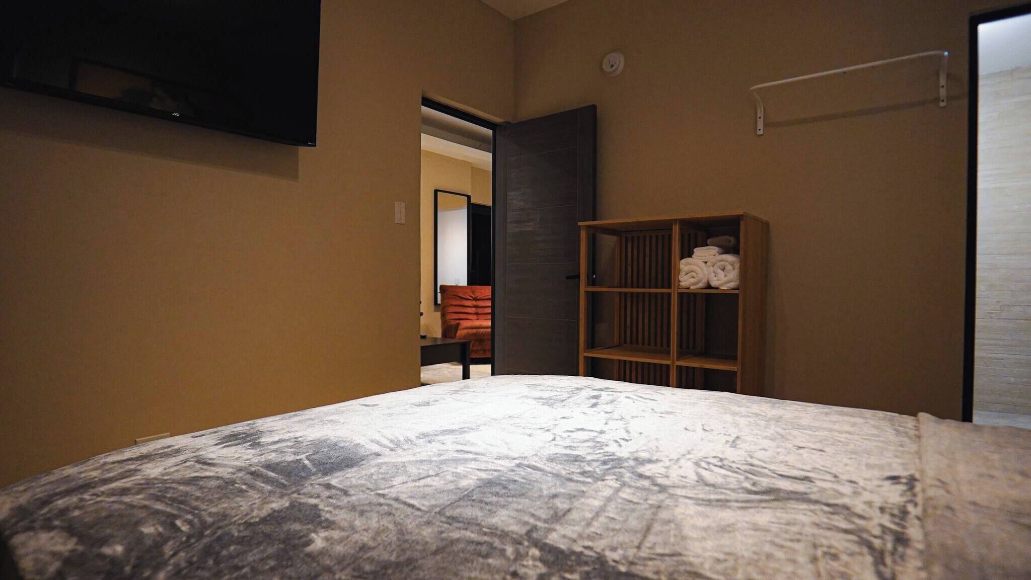 Une chambre à coucher avec un lit, une armoire en bois et un téléviseur fixé au mur.