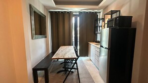 Cozinha compacta com mesa e cadeiras, geladeira e micro-ondas.