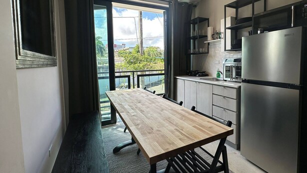 Cozinha moderna com mesa de jantar de madeira, geladeira de aço inoxidável e vista para o verde lá fora.