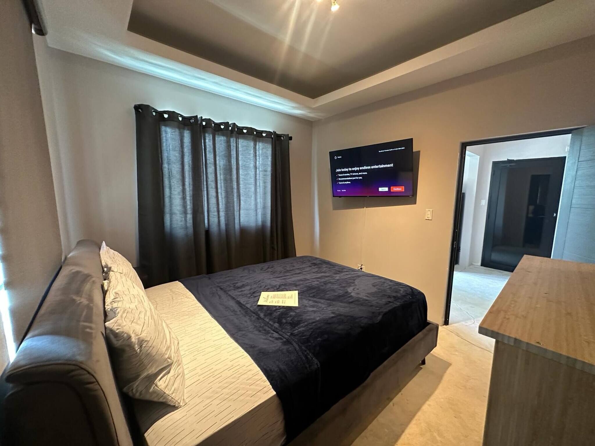 Ein Schlafzimmer mit Bett, Wandfernseher und Schreibtisch.