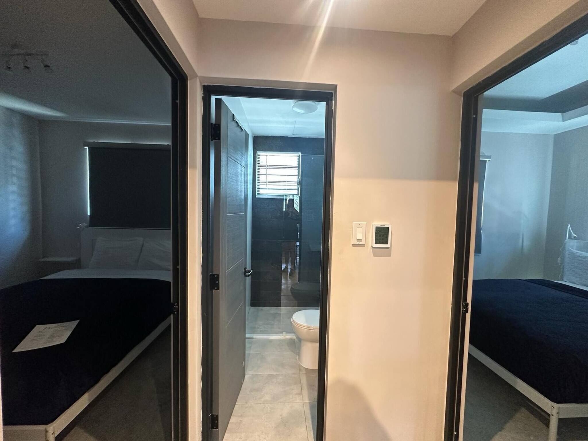 Een moderne hotelkamer met een groot bed, een aparte badkamer en een schuifdeur naar een andere kamer.