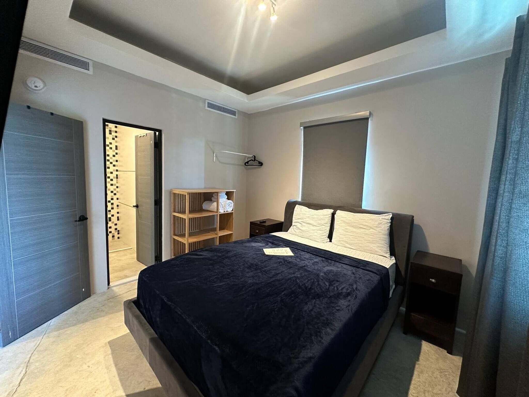 A bedroom with a bed, a wardrobe, a nightstand, and a window.