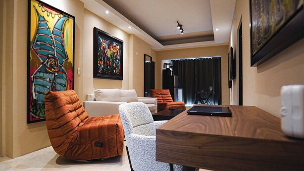 A modern living room with a sofa, armchair, and a wooden coffee table. There are two paintings on the walls and a ceiling light. - Dream apt: 8BD, 6BA, parking. (San Juan)